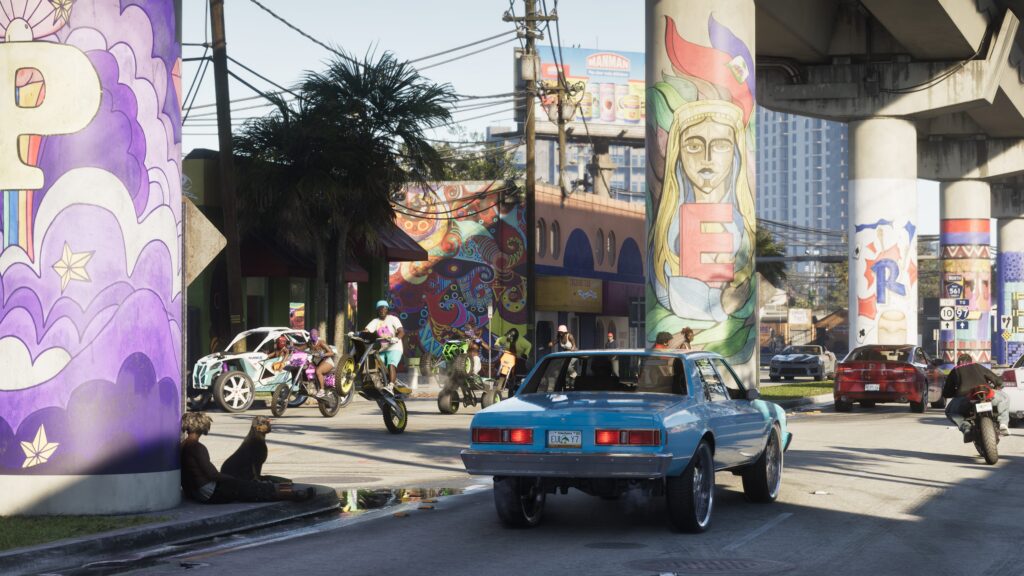 Traffic and motorcyclists beneath a mural-covered overpass in an official GTA VI Vice City image.